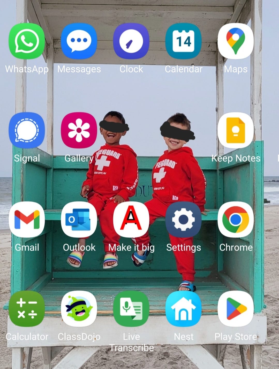 ID: Screenshot of my phone’s home screen, with two apps missing from the center, revealing the faces of two young boys smiling in matching red sweatsuits, sitting in a green and white lifeguard stand. Their eyes are blacked out for privacy.