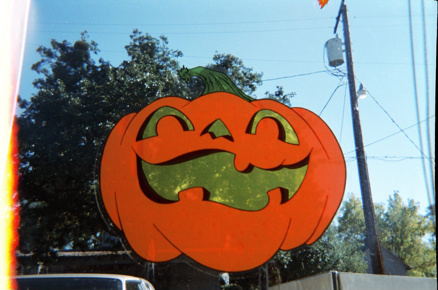 An orange, smiling pumpkin decal sits in the center of a window pane