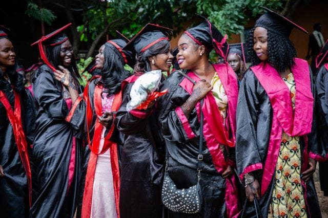 A group of young Sudanese women in black and red graduation regalia