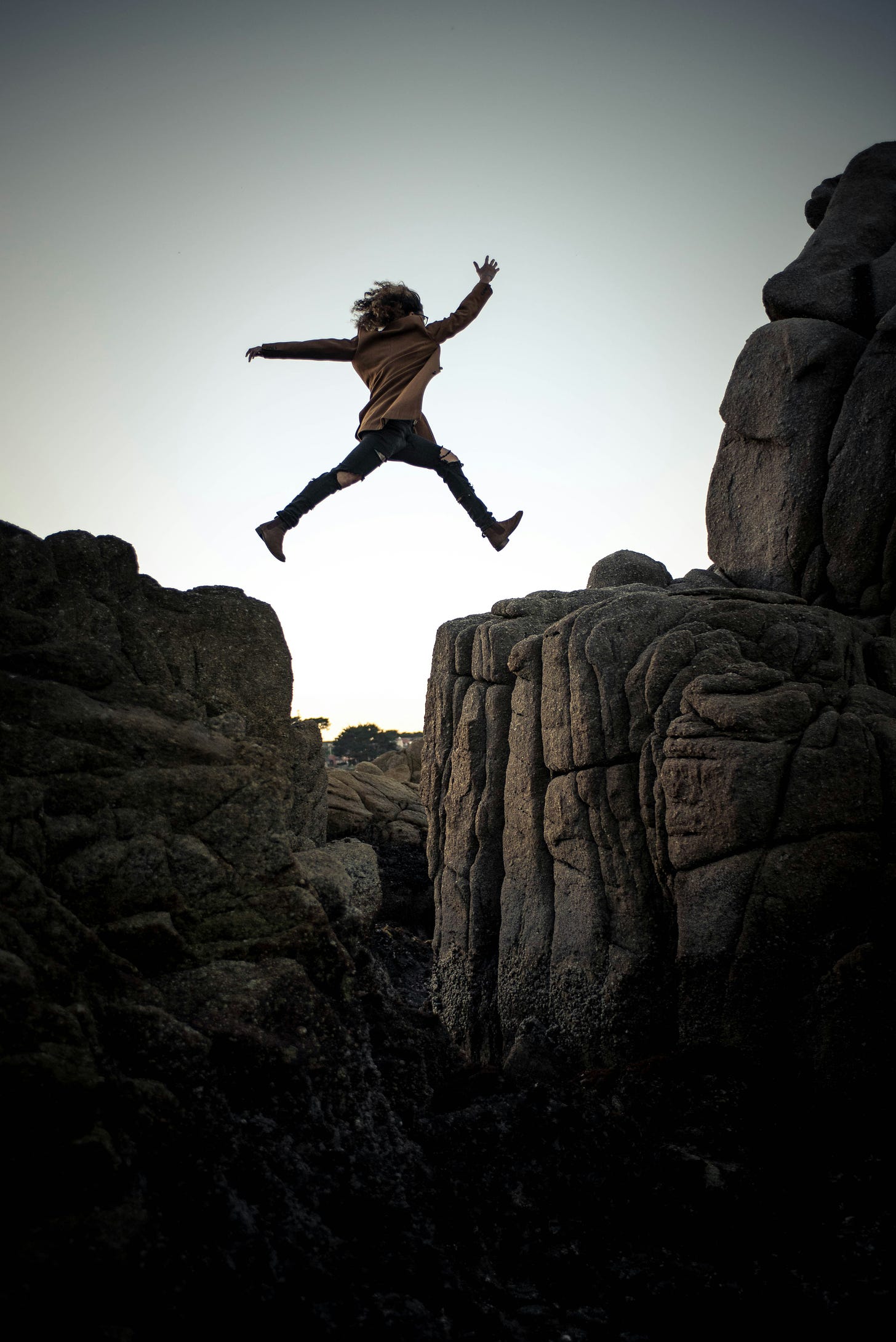 woman leaping across mountain boulders