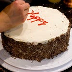 A cake that someone is writing "Happy" on. "Writing on Cake" by FoodMayhem.com is licensed under CC BY-NC-ND 2.0. 