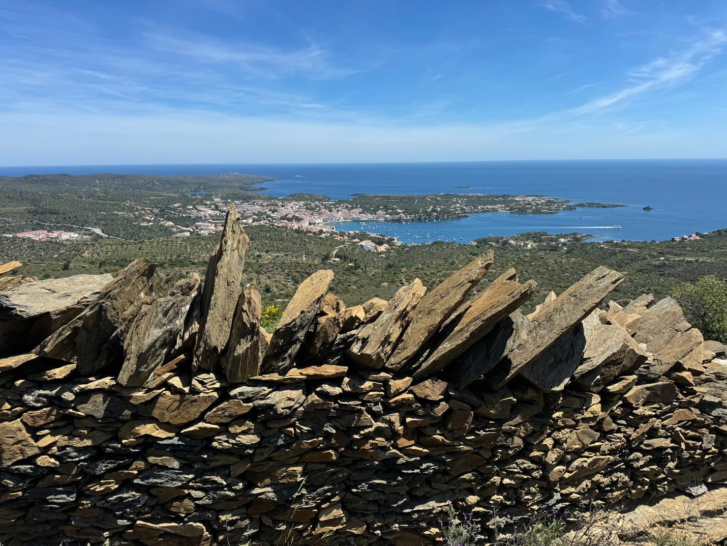 A stone wall with a body of water in the background

Description automatically generated