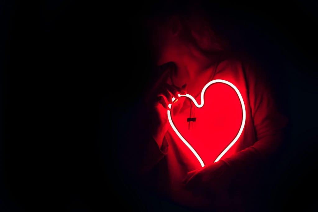 Woman holding heart shaped red neon signage