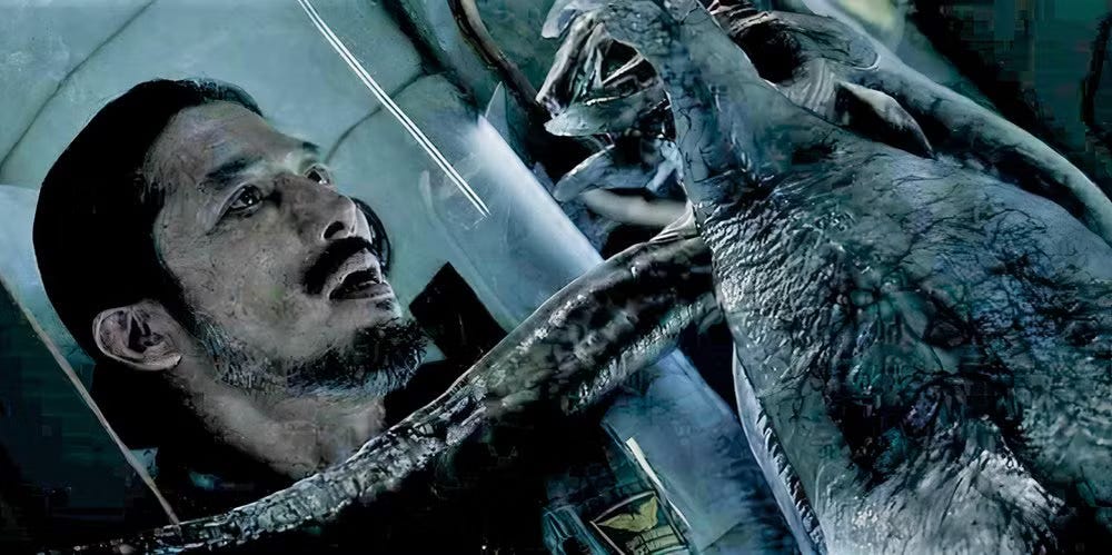 bearded man behind glass looks frightened by a squishy tentacle monster outside