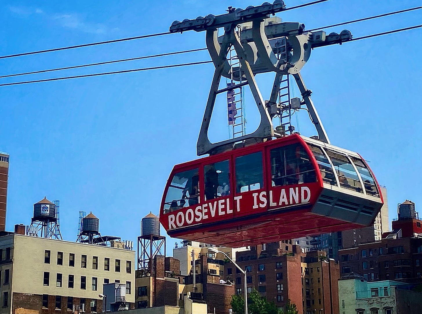 The Roosevelt Island tram suspended in front of four water towers.