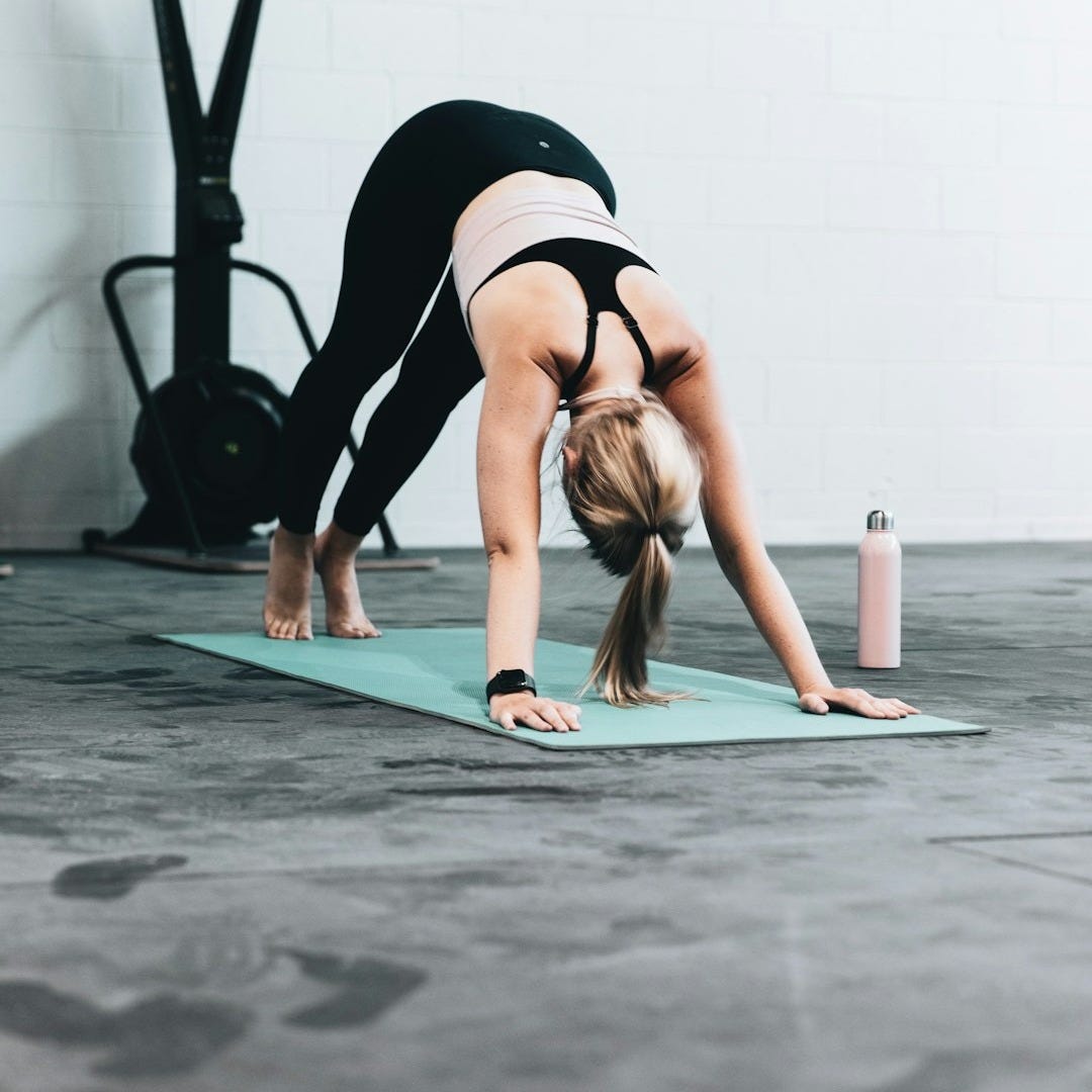 woman in black sports bra and blue denim jeans doing yoga woman in black sports bra and blue denim jeans doing yoga