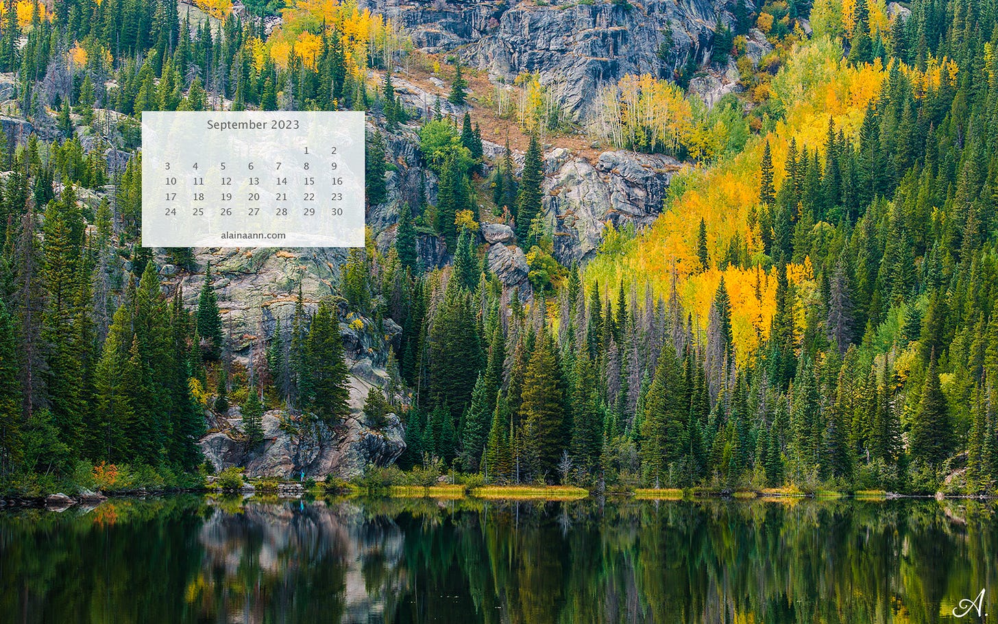 Mountainside pine trees and yellow aspens reflecting into a lake below. A transparent white calendar for the month of September is in the upper left corner of the photo.