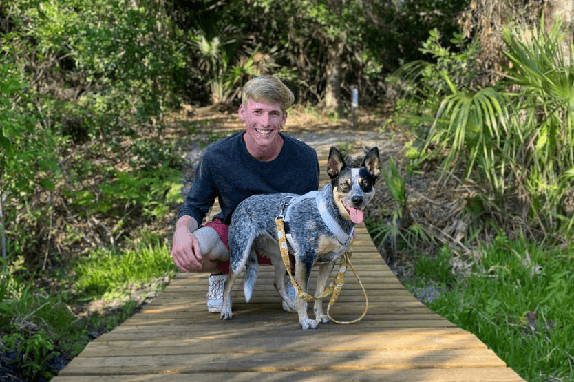 Scout the blue heeler posing with her owner, Sean, on a hiking trail in Wickham Park in Melbourne, FL