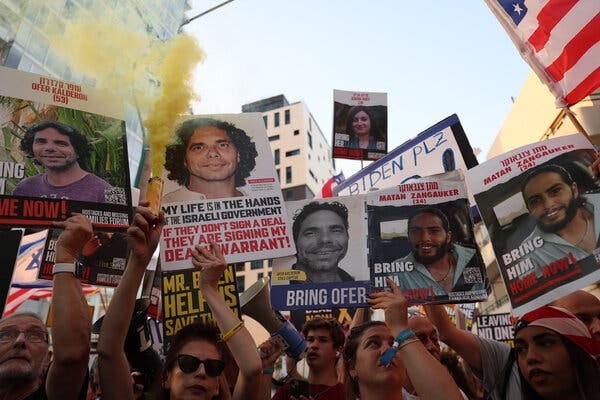 People holding signs saying “Bring Him Home Now,” and other messages at a protest.