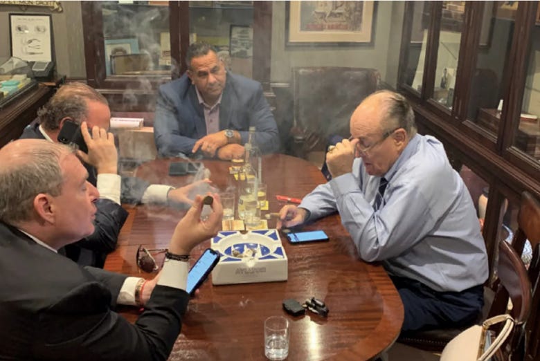 A group of men sitting around a table with smoke

Description automatically generated