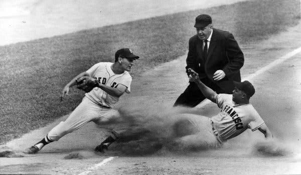 Willie Mays slides into third base, dust flies.