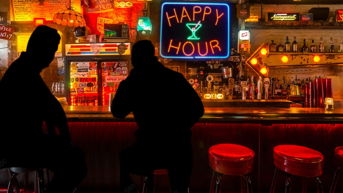 Two men sitting on barstools in a dive bar.