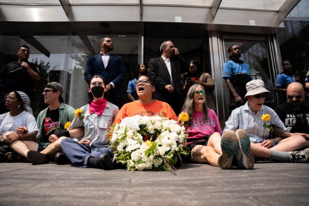 Protesters sit-in and block the entrance to Citi's office in Manhattan during the Migrant and Displaced Peoples Week