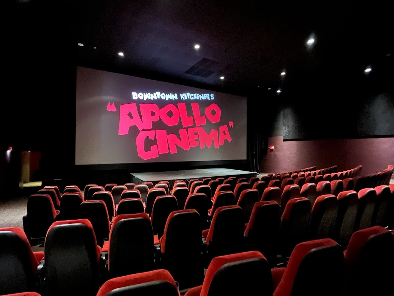 Image of Apollo Cinema's theatre - red seats with a large screen that says, Downtown Kitchener's Apollo Cinema