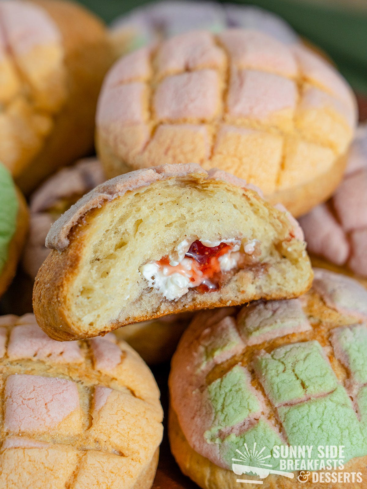 Rainbow conchas, one cut in half to show the inside.