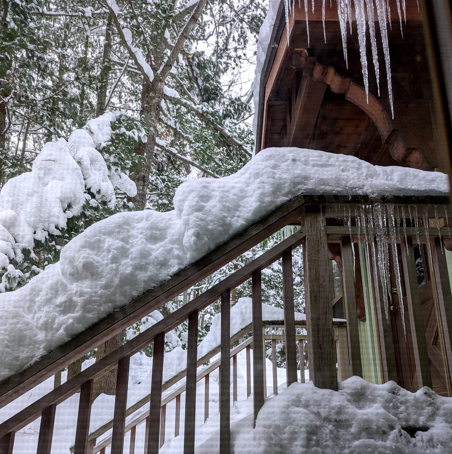 A snow-covered staircase leading up to a wooden porch, surrounded by tall evergreen trees heavy with snow. Icicles hang from the roof above, and the scene captures the stillness of winter. A snow-covered staircase leading up to a wooden porch, surrounded by tall evergreen trees heavy with snow. Icicles hang from the roof above, and the scene captures the stillness of winter.