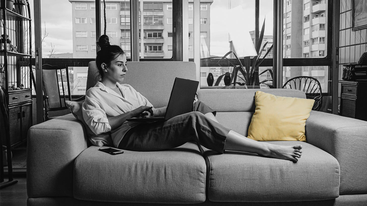 Hawk faced woman looks down on her laptop as she works from her couch