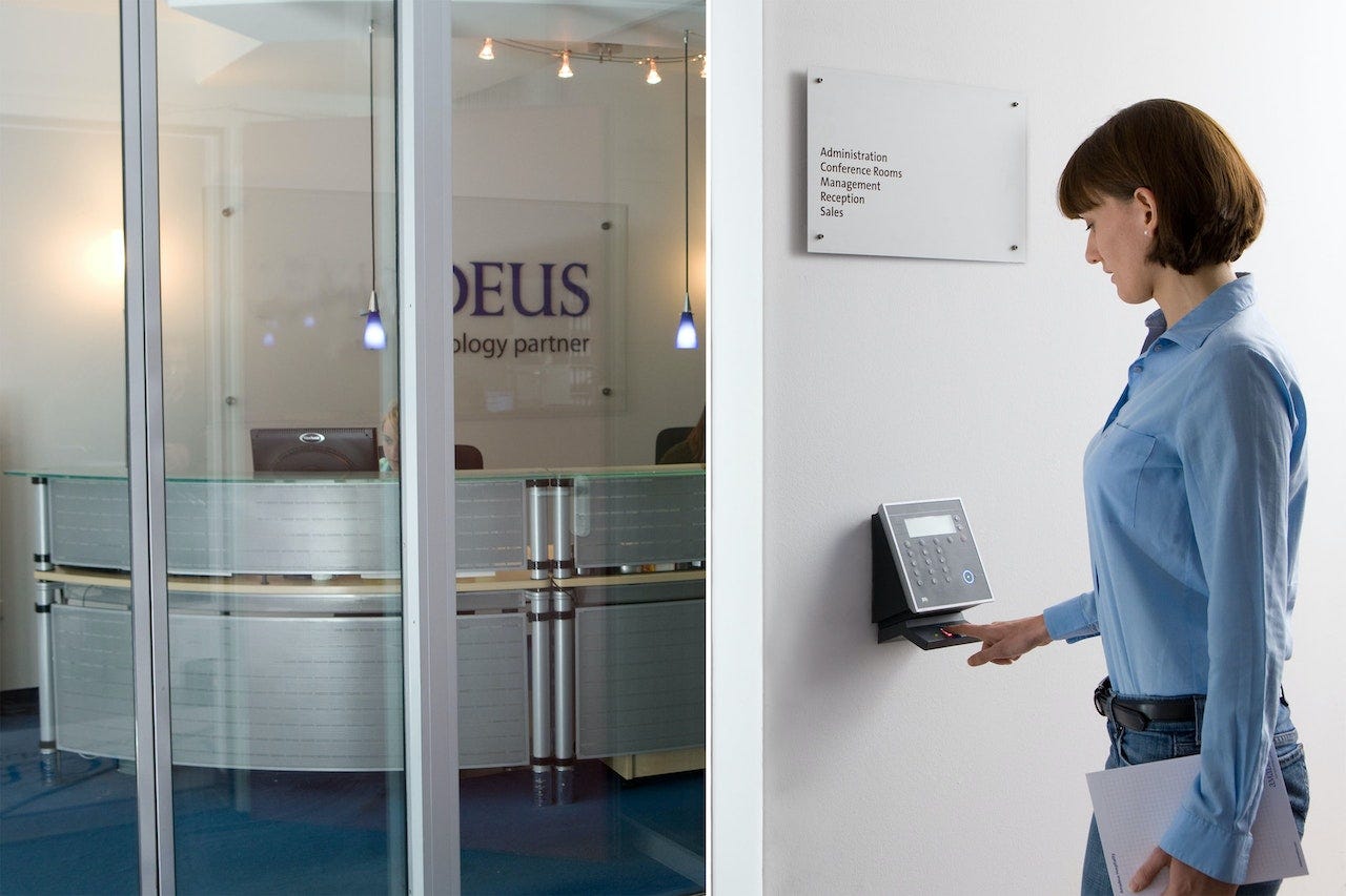 A photo of a woman scanning her fingerprint to enter an office