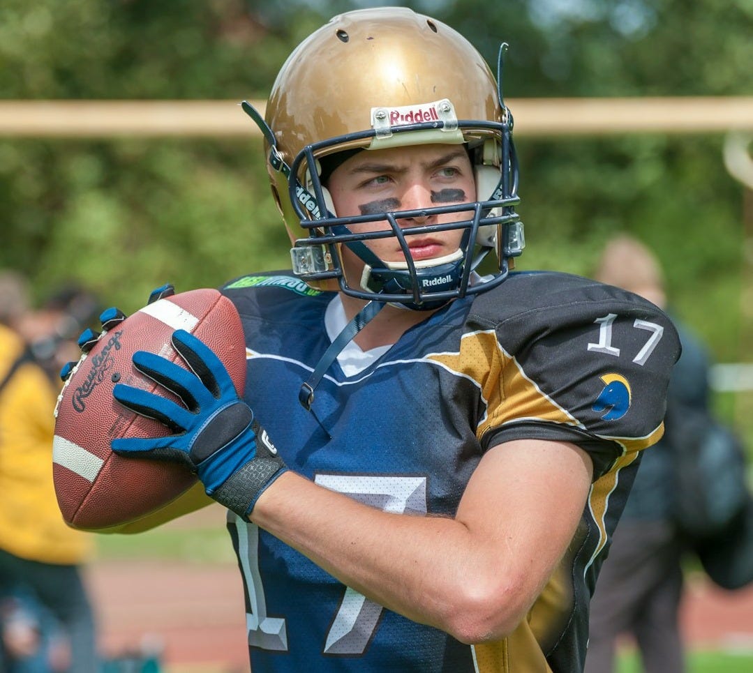 a football player holding a football on a field a football player holding a football on a field