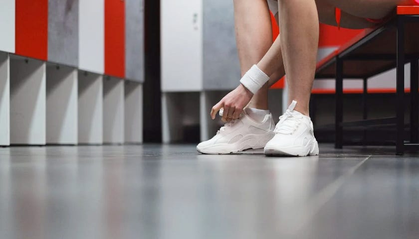 A woman is tying her shoe in the female locker room. 