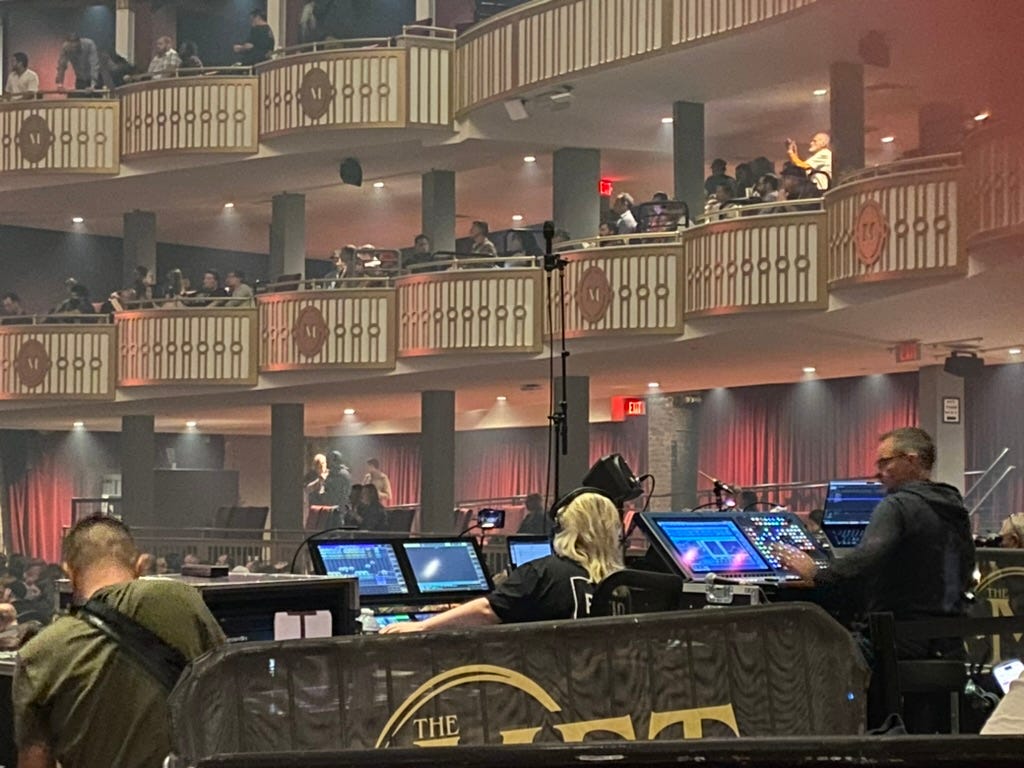 A group of people in a large room with a large balcony and a large building with a large balcony and a large building with a red curtain and a red curtain

Description automatically generated