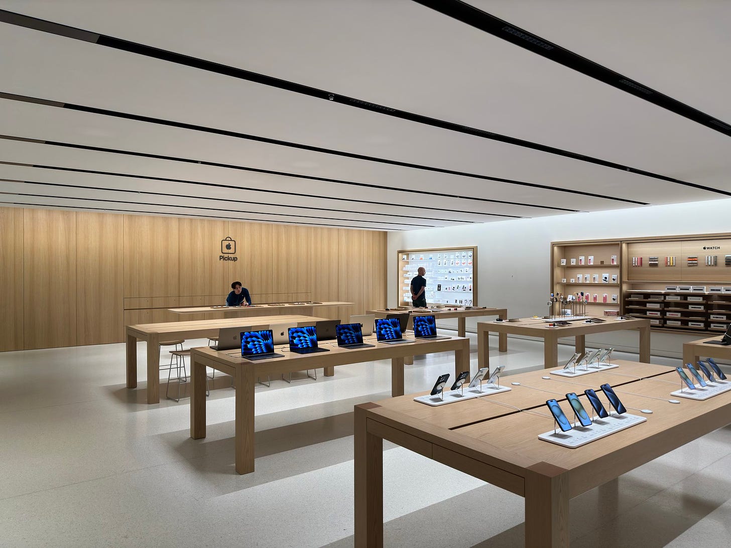 The ground level of Apple Shinsaibashi. The store is mostly empty, and one employee stands behind the Apple Pickup counter.