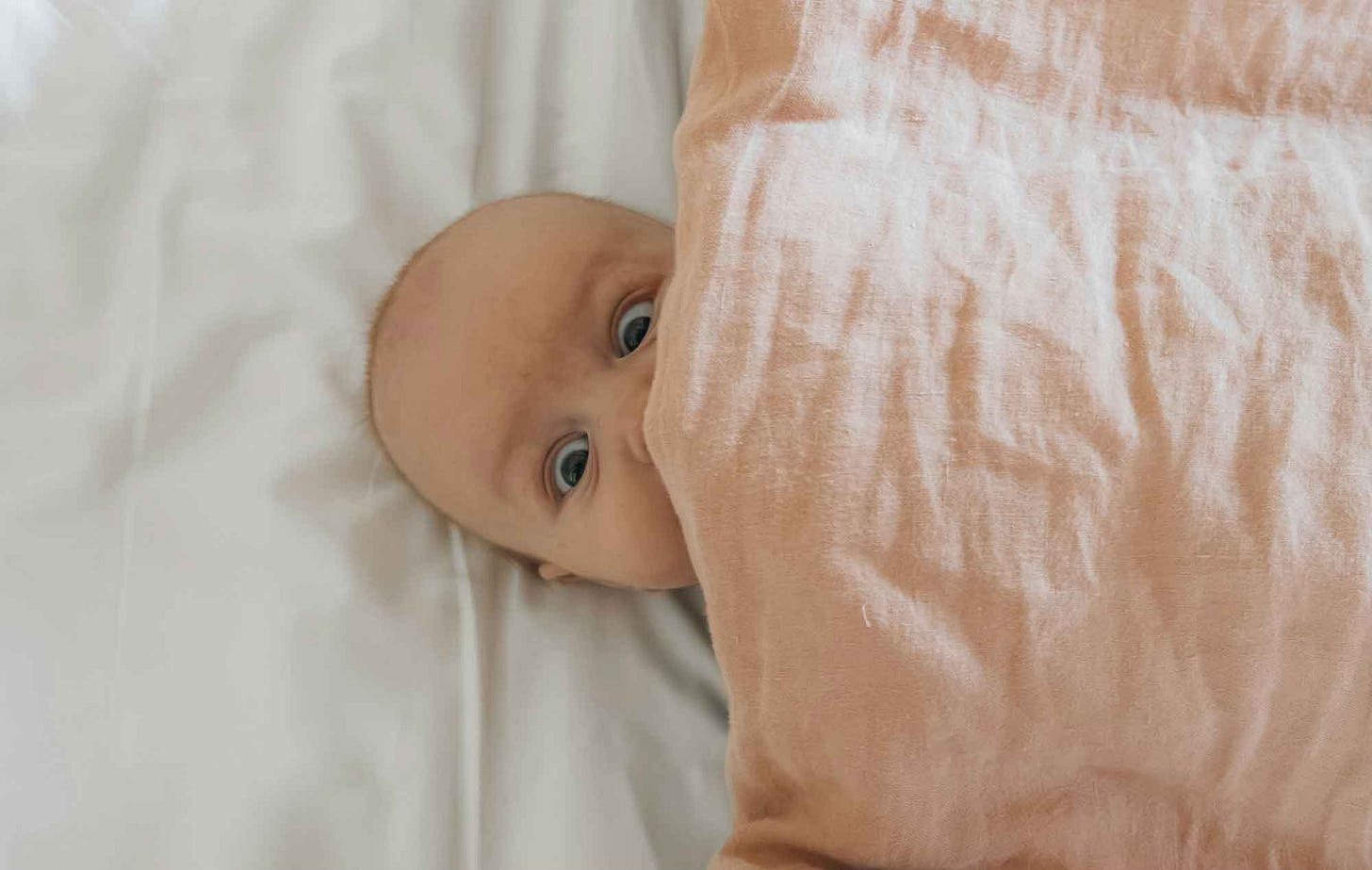 A baby peeking from under a blanket A baby peeking from under a blanket