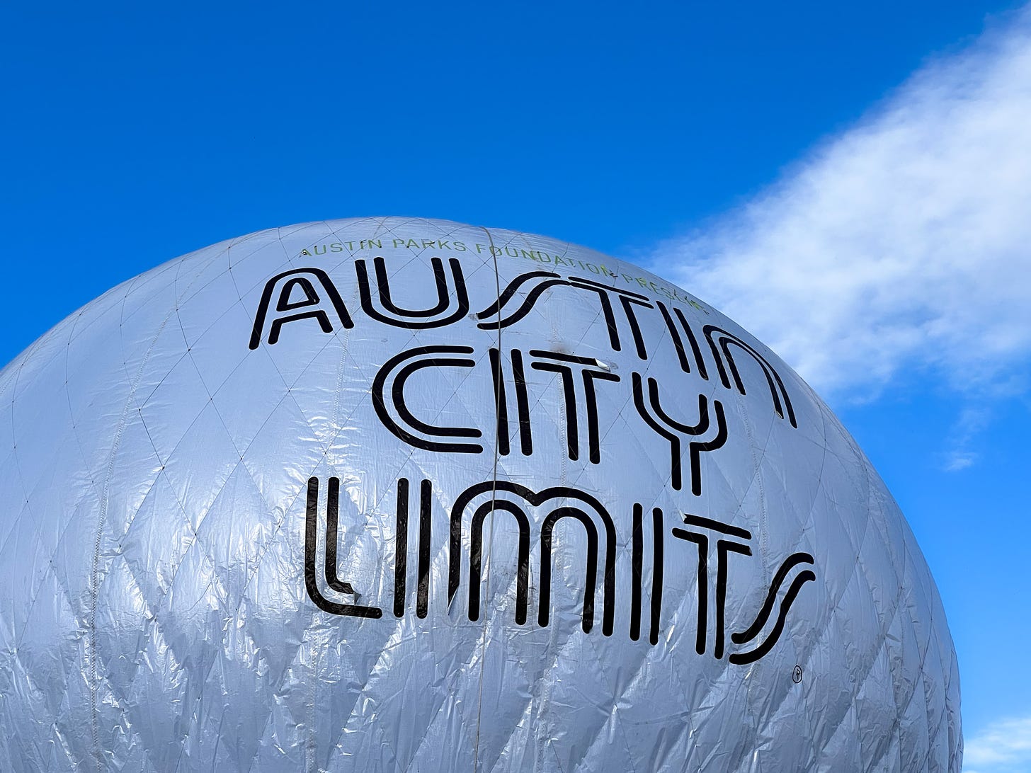 A large white mylar baloon against a blue sky with  these words in large block print: Austin City Limits