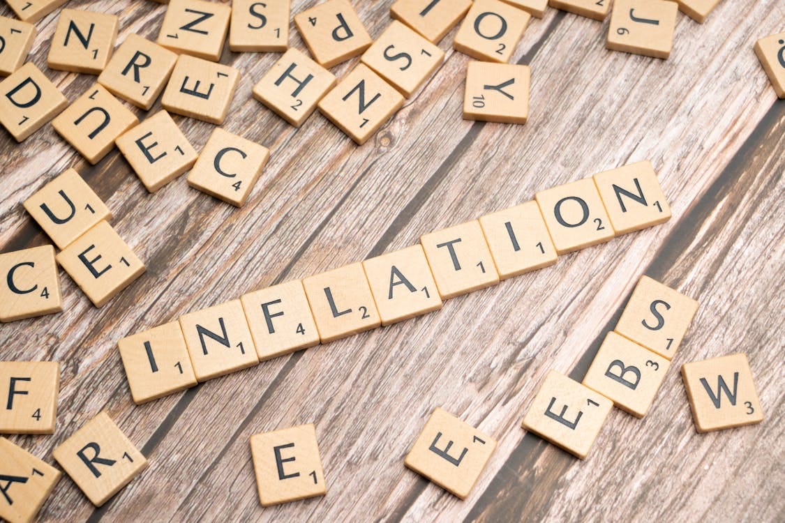 Free Wooden letter tiles forming the word 'inflation' on a rustic wooden surface, symbolizing economic themes. Stock Photo