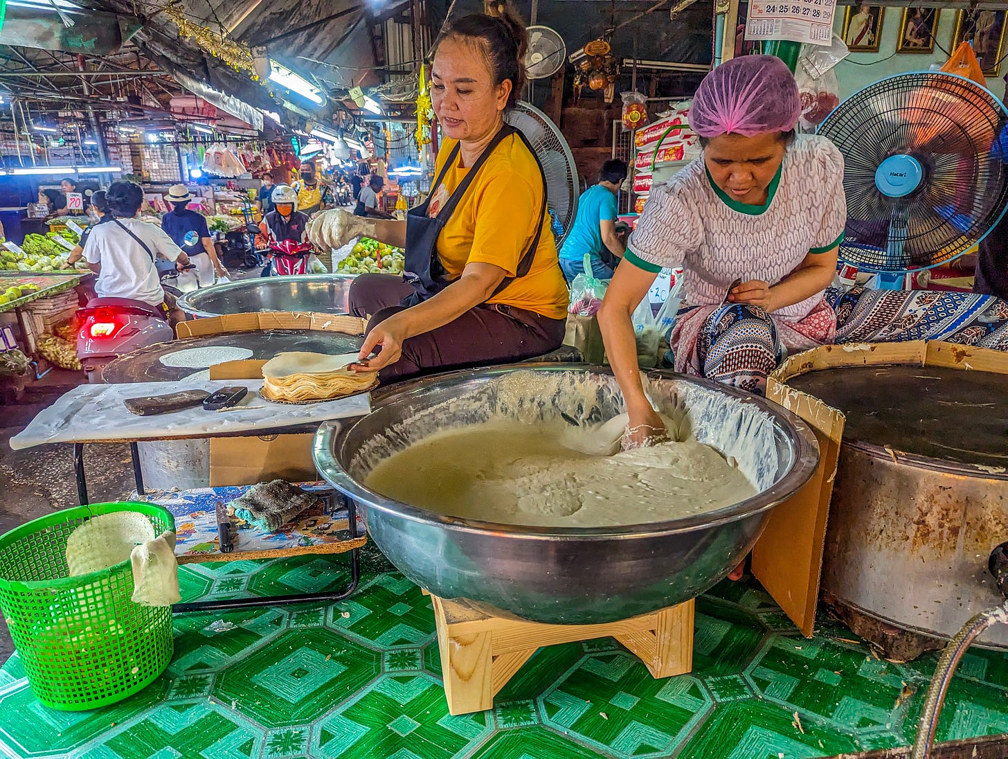 Two women preparing batter to be fried. 