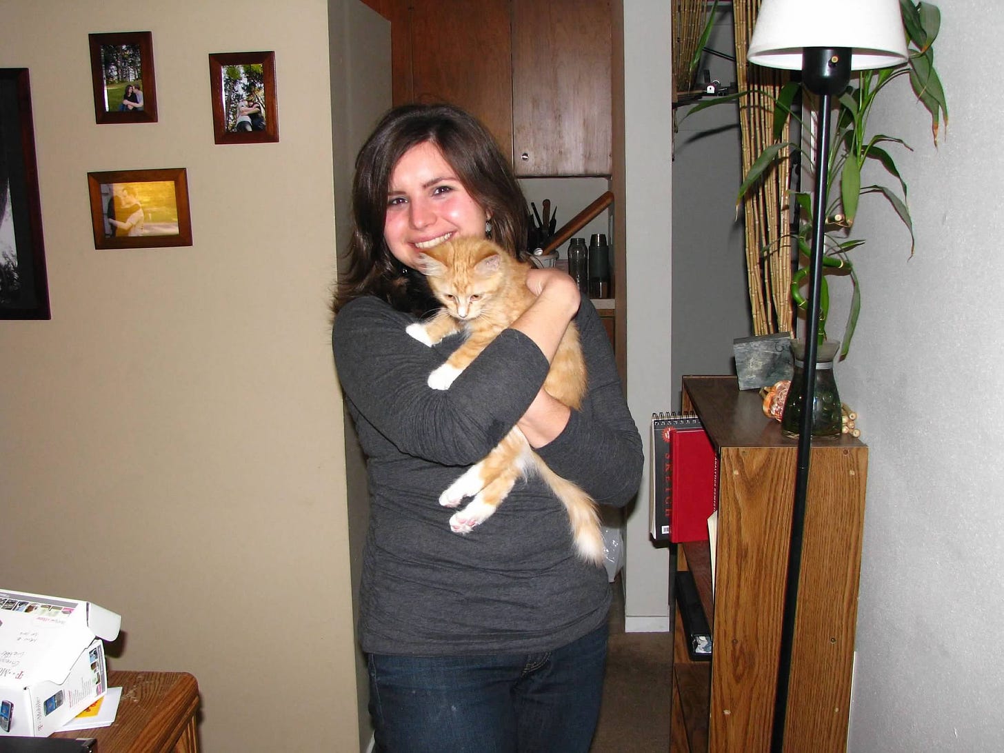 Me at 24 years old, smiling and embracing an orange kitten with white feet