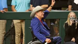 Greg Abbott in a cowboy hat and wheelchair waving to a crowd