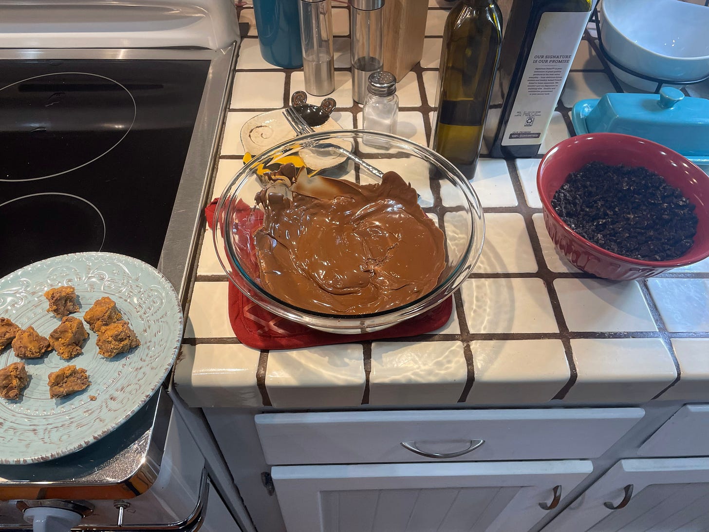 Peanut butter balls next to melted chocolate next to oreo dust