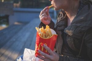 woman eating french fries at dusk