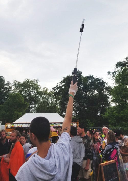 une personne tenant un tpe au bout d'un selfie stick