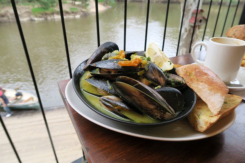 A plate of mussels and bread on the edge of a table, overlooking the Yarra River in Melbourne.