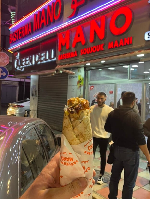 Me holding a shawarma in front of a restaurant.