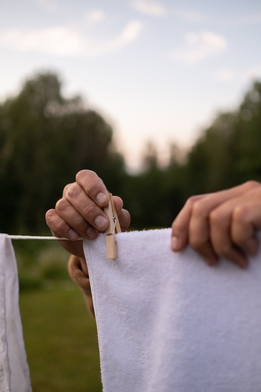 close up view of hands holding laundry and clamp