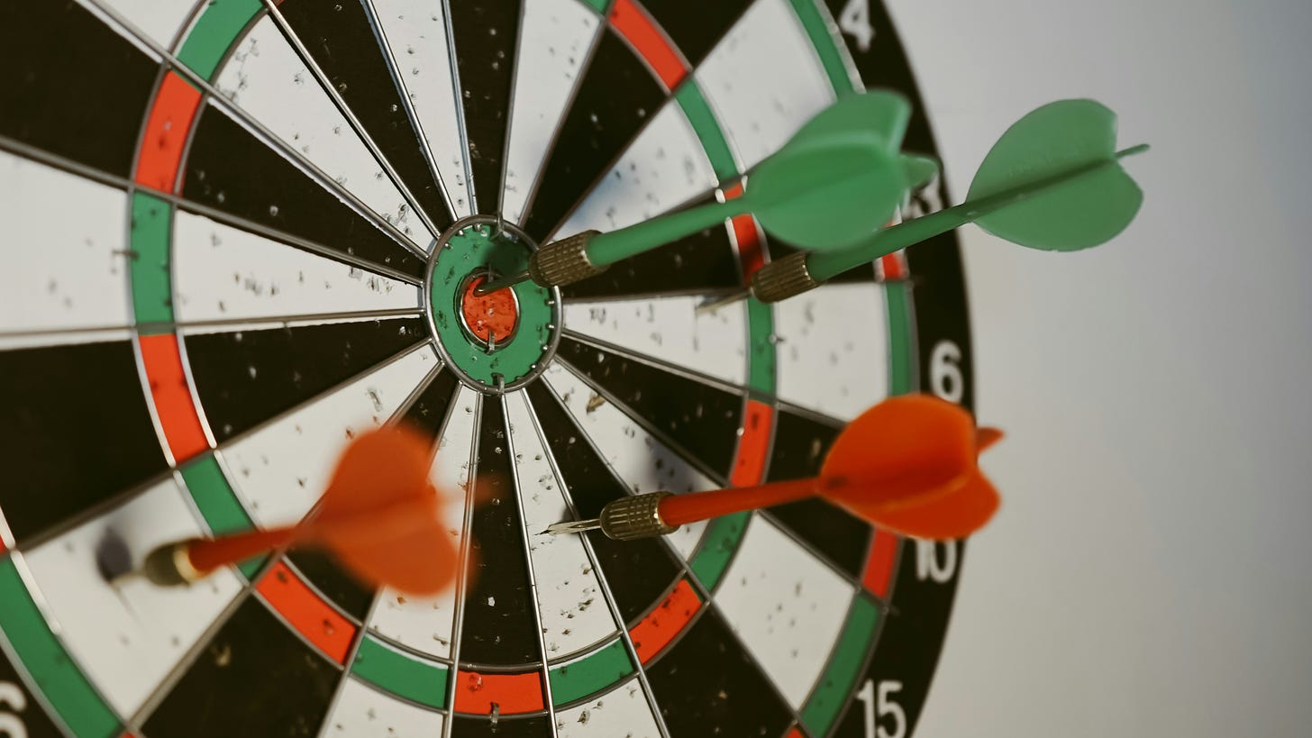 Photo of a dartboard with 4 darts: 1 'bullseye', 3 off-center
