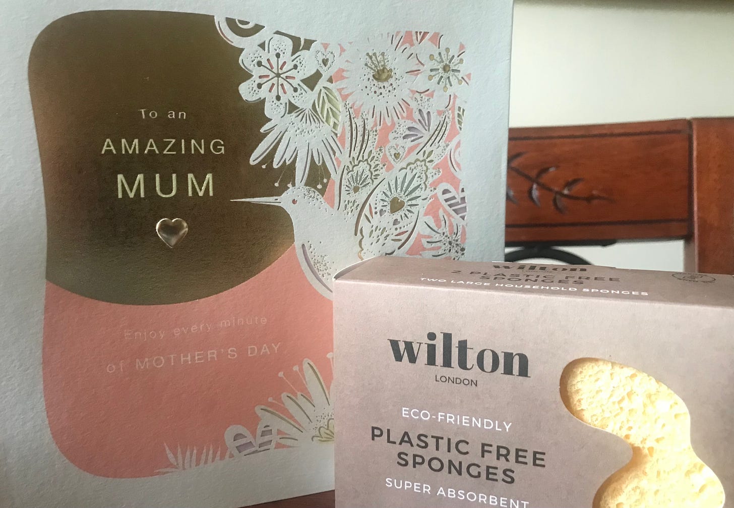 Mother’s Day card in the background with a plastic-free bamboo material sponge shown in brown box packaging