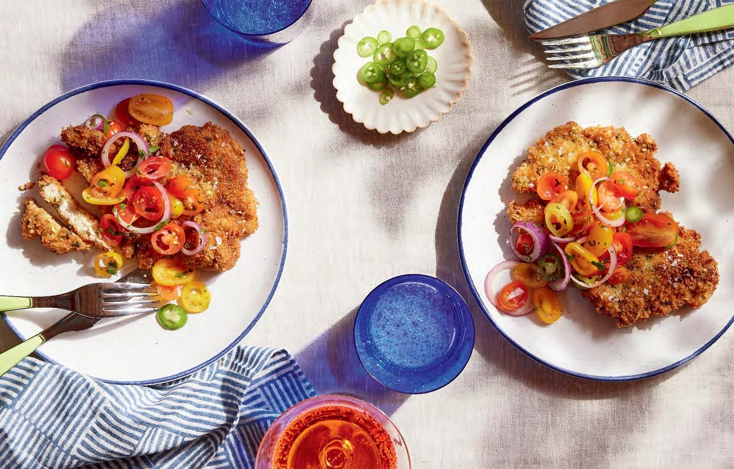 Coriander chicken katsu with cherry tomatoes on two plates.