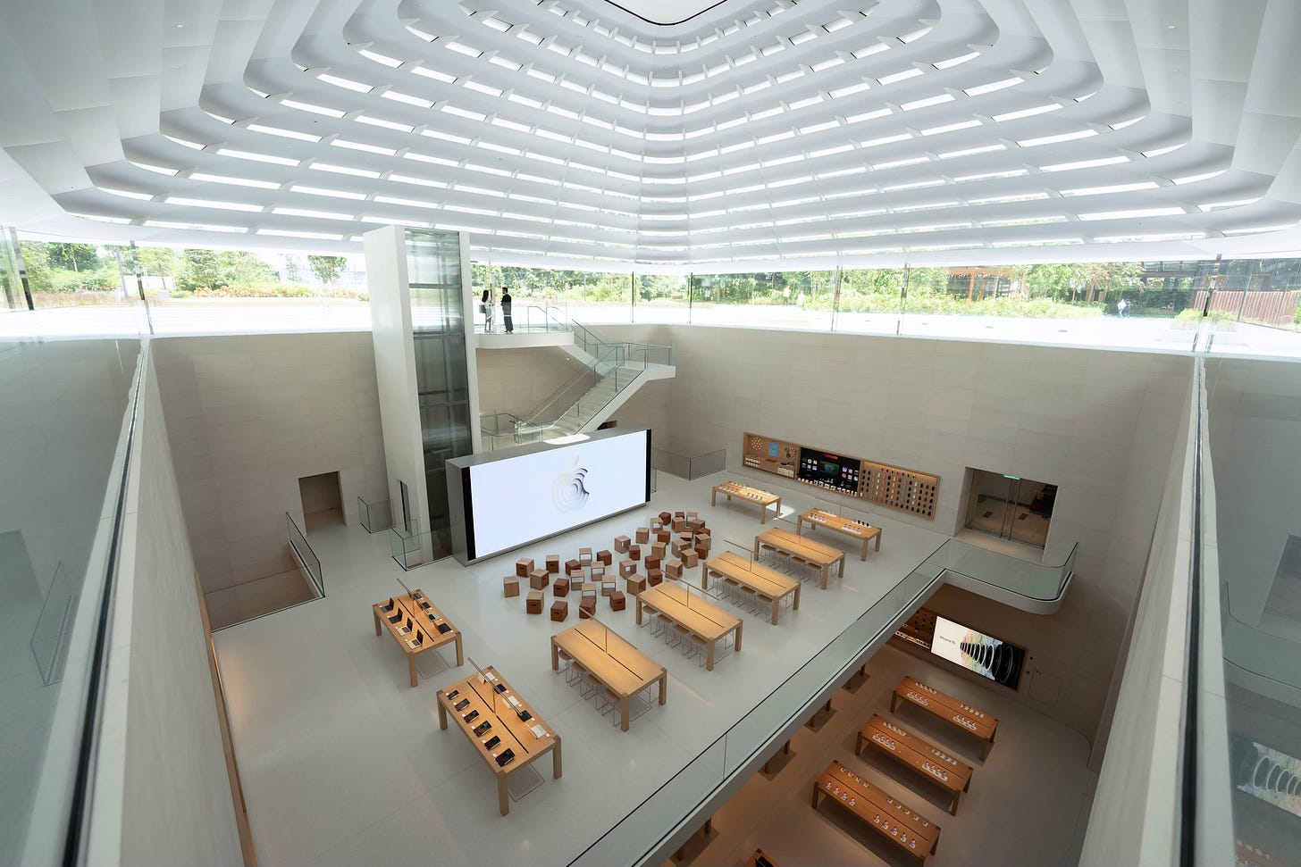 The interior of Apple The Exchange TRX viewed from the canopy looking down. The Forum is arranged on level 2, and tables appear at the edge of the frame on level 1.