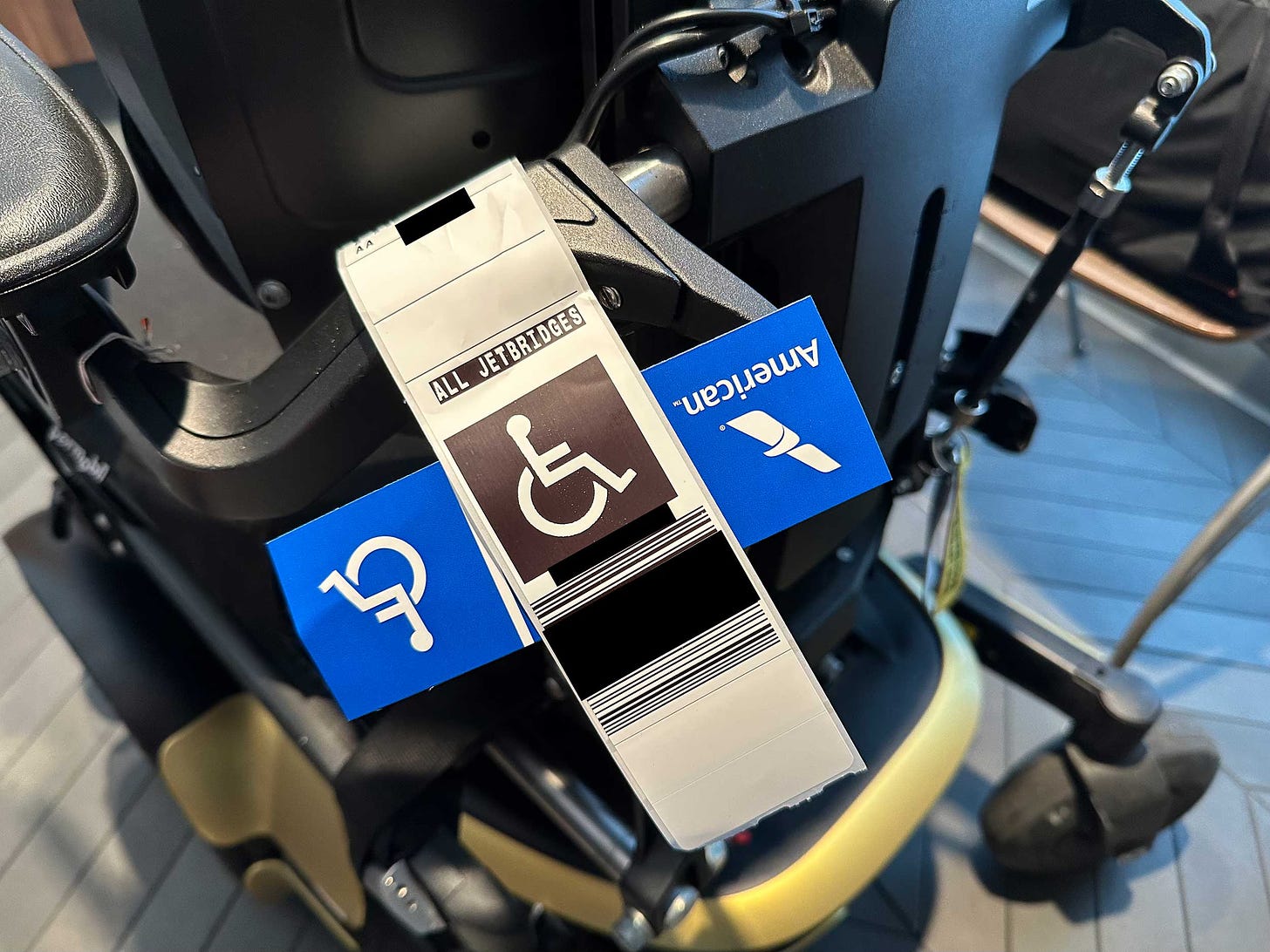 Close up view of baggage tag affixed to armrest of power wheelchair.