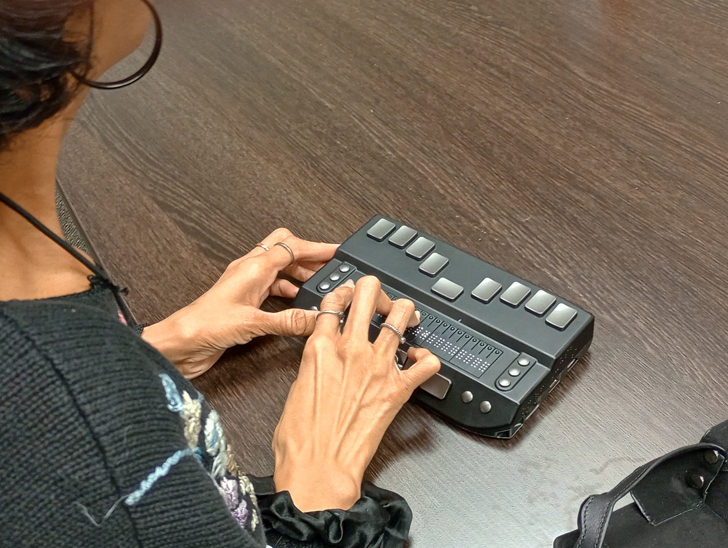 A woman using a Braille eReader - A closeup of a person's hands using a Braille eReader, a small portable electronic reading device for braille users.