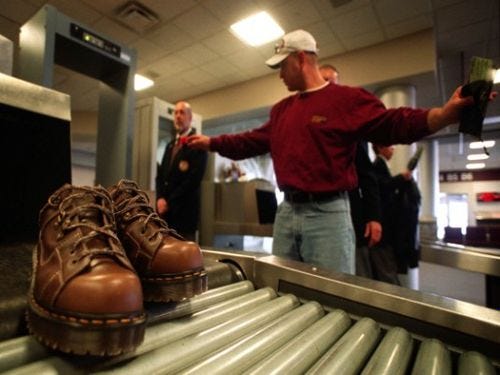SHOES OFF: Dave Peterson, of Cedar Rapids, Iowa, is searched by airport security as his shoes roll off the conveyor belt of an X-ray machine at the Eastern Iowa Airport in Cedar Rapids. Six months after Sept. 11, more Americans are flying again but they know anything could happen anywhere at any time.