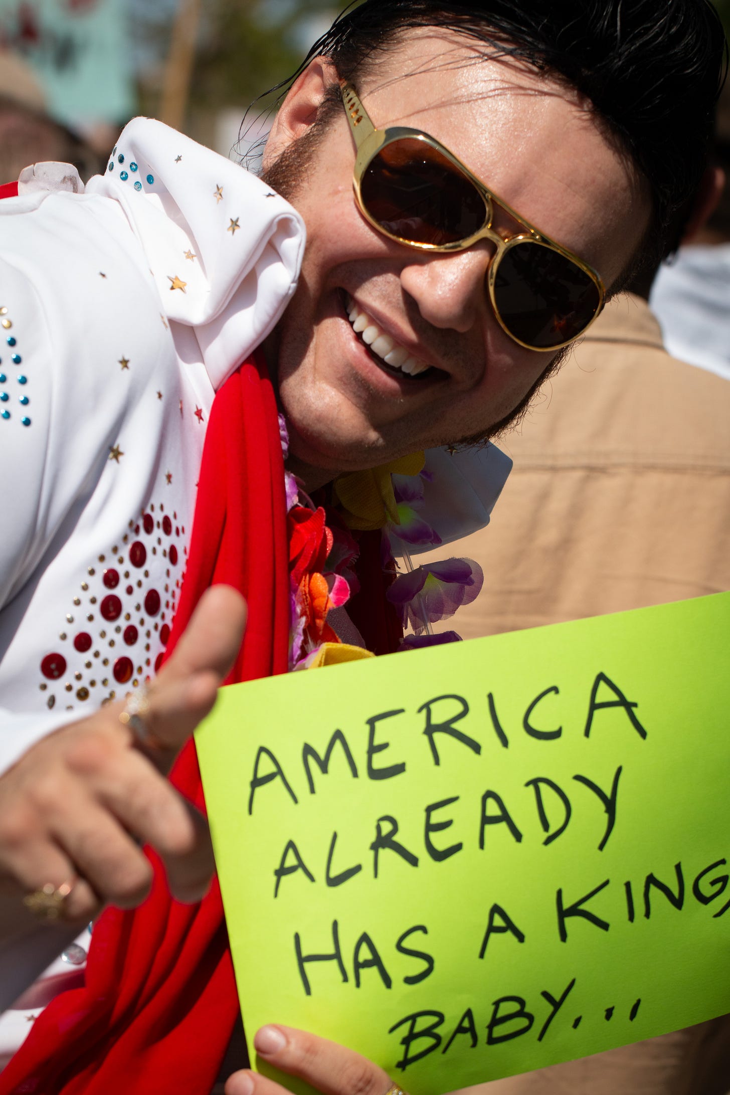 An Elvis impersonator had a neon green sign reading, "America already has a king, baby."