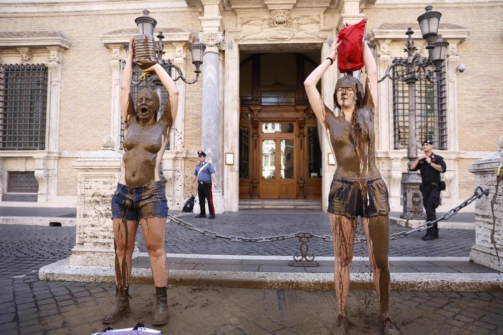 Climate activists of the 'Last Generation' shower themselves with mud in front of the Senate building in Rome, Italy, Tuesday, May 23, 2023. (Cecilia Fabiano/LaPresse via AP)