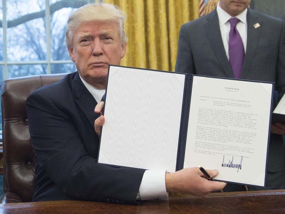 U.S. President Donald Trump holds up an executive order withdrawing the US from the Trans-Pacific... [+] Partnership after signing it in the Oval Office of the White House in Washington, DC, January 23, 2017. (SAUL LOEB/AFP/Getty Images)