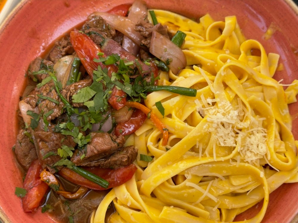 Generous portion of beef stir-fry with pasta in yellow pepper sauce