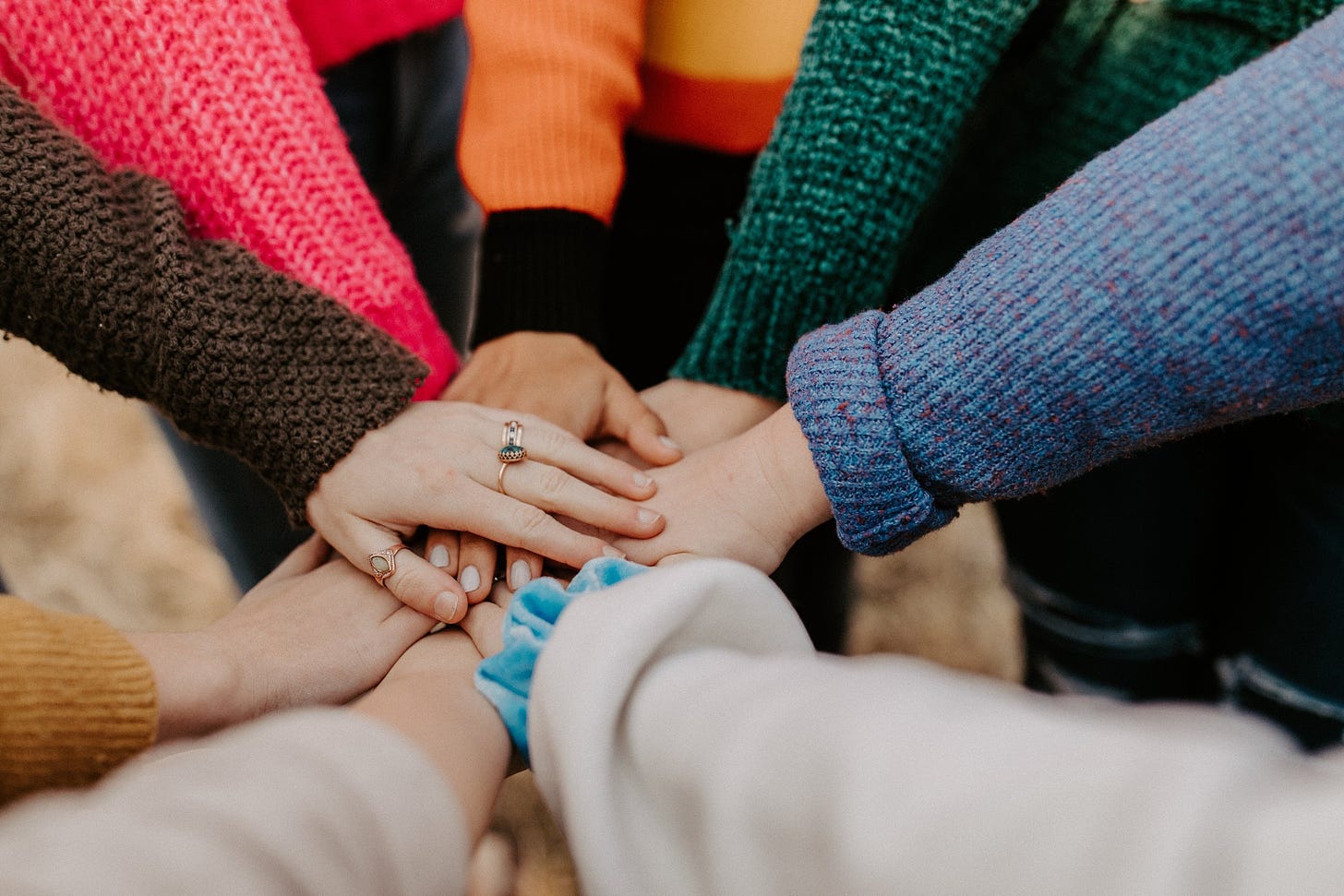 Close up photo of multiple people putting their hands together in a pile